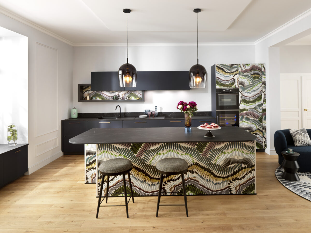 Die Designküche besteht aus einer Küchenzeile und kurzer Hochwandstrecke. Die Kücheninsel mit übertiefer Arbeitsplatte schafft Raum für eine Sitzmöglichkeit.