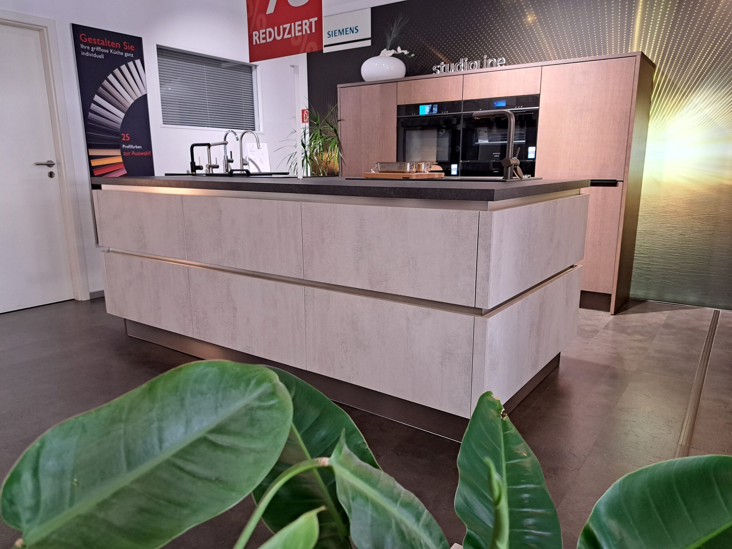 Moderne Abverkaufs-Küche mit einer großen, Kücheninsel und eingebauten Küchengeräten in den Hochschränken.