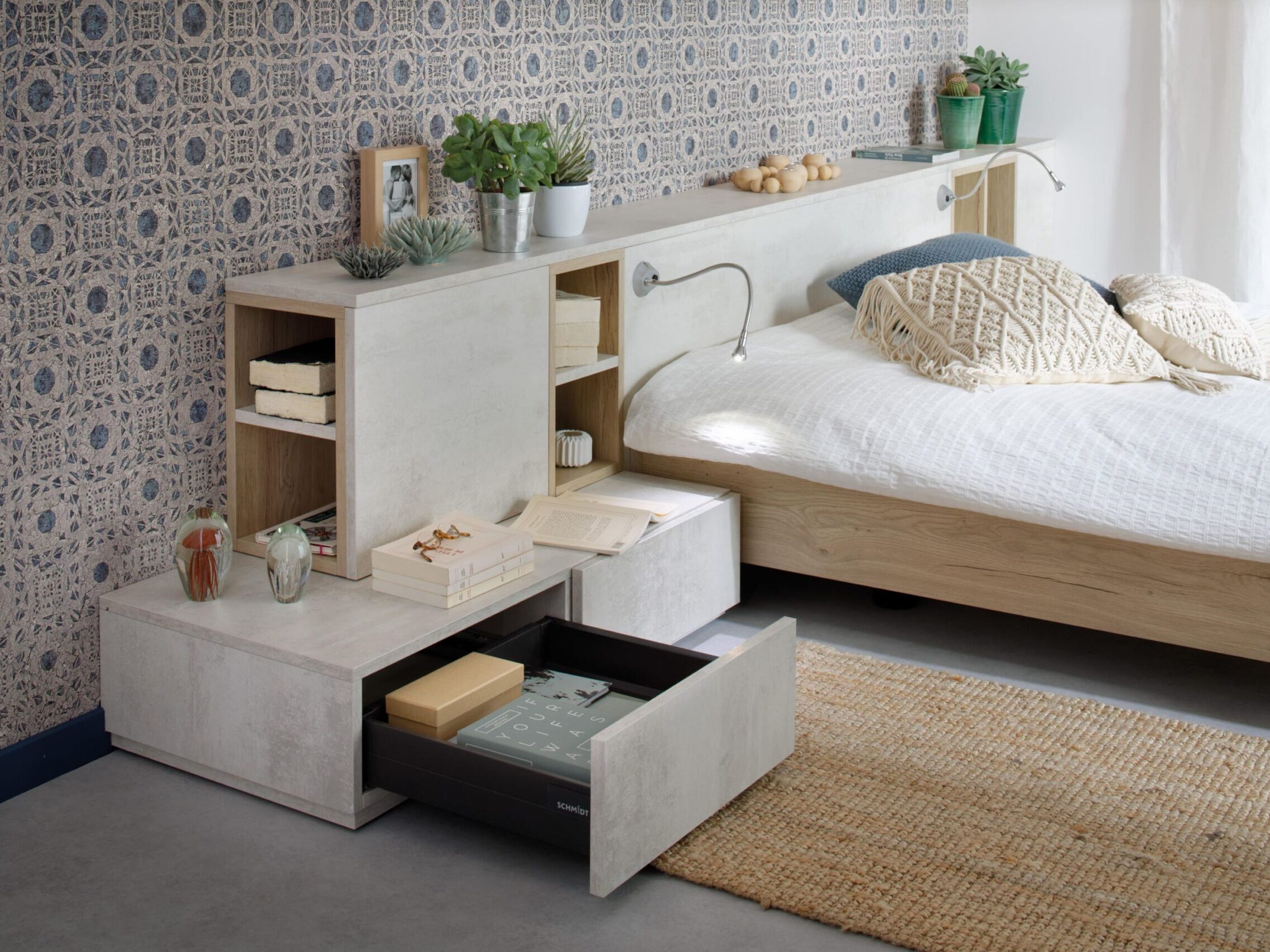 Ein Bettgestell aus Holz mit integriertem Kopfteil und einer Nachttisch-Aufbewahrungseinheit mit offenen Regalfächern und einer ausziehbaren Schublade, das für ein modernes, individuelles Schlafzimmer steht.